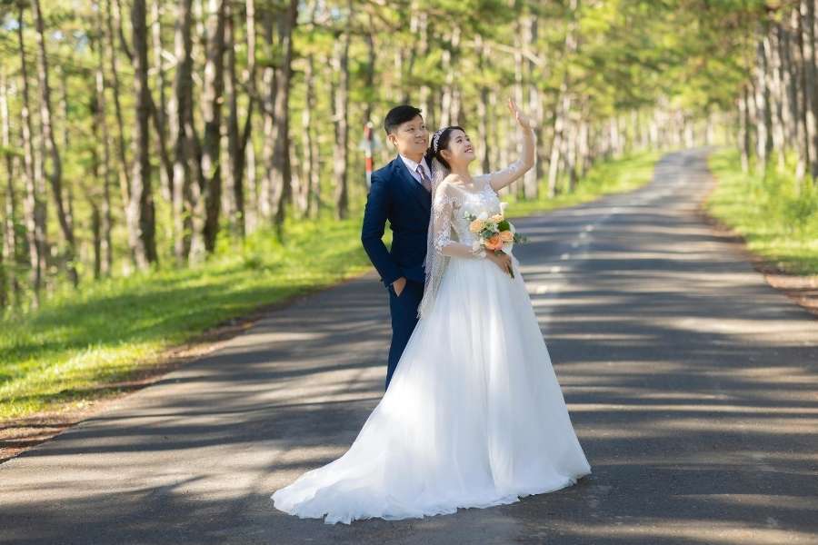 Couple de mariés posant sur une route forestière pour un book photo de mariage