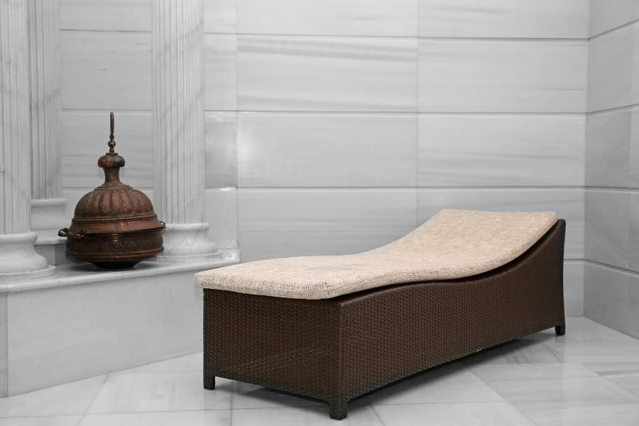 Chauffeuse ergonomique et élégante installée dans une pièce en marbre clair pour un hammam oriental.