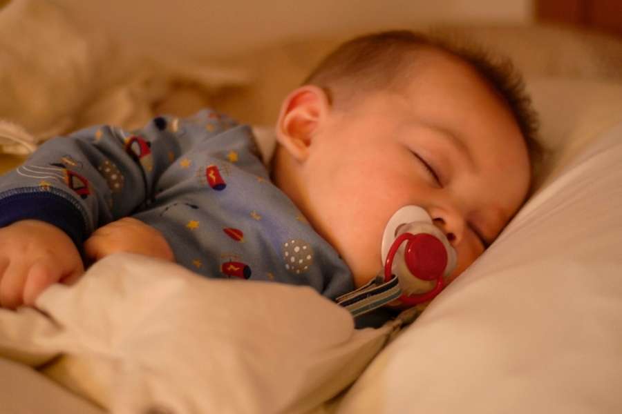 Gros plan sur un bébé qui dort profondément avec une tétine pour illustrer le moment où bébé fait ses nuits.